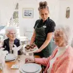 nursing staff at residential care home in Bolton serves up delicious cupcakes to happy elderly care home residents