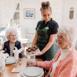 nursing staff at residential care home in Bolton serves up delicious cupcakes to happy elderly care home residents