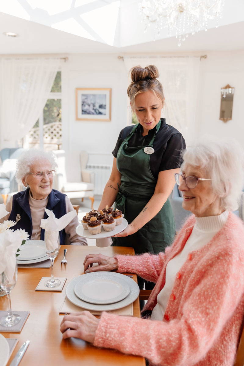 nursing staff at residential care home in Bolton serves up delicious cupcakes to happy elderly care home residents